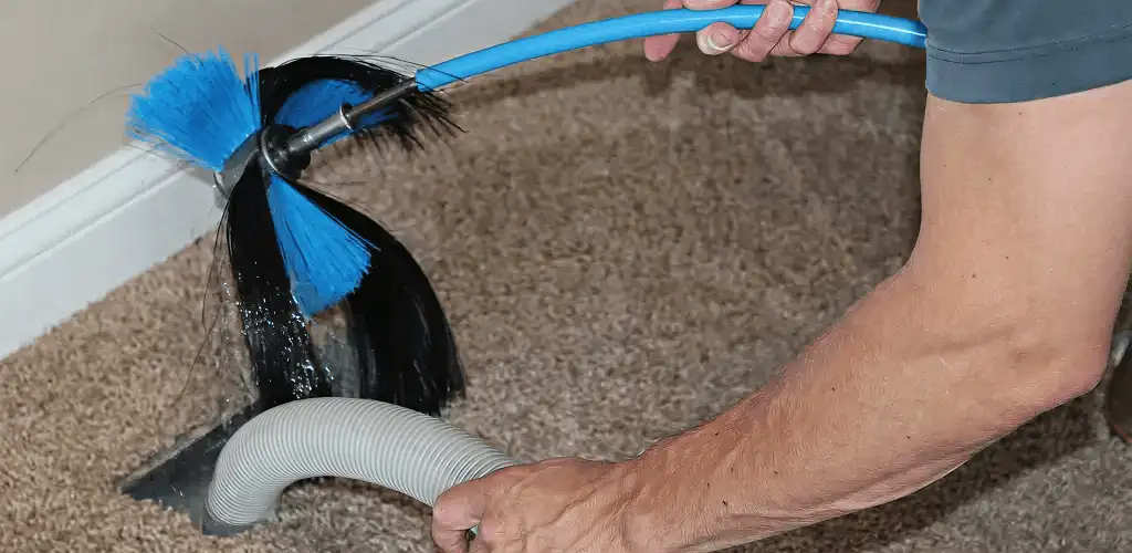 Dryer vent cleaning technician brushing lint from a vent line in Rockford, IL
