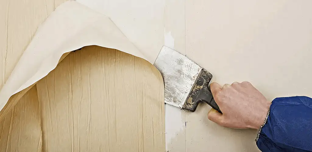 Handyman removing wallpaper with a scraper for wall preparation in Rockford, IL