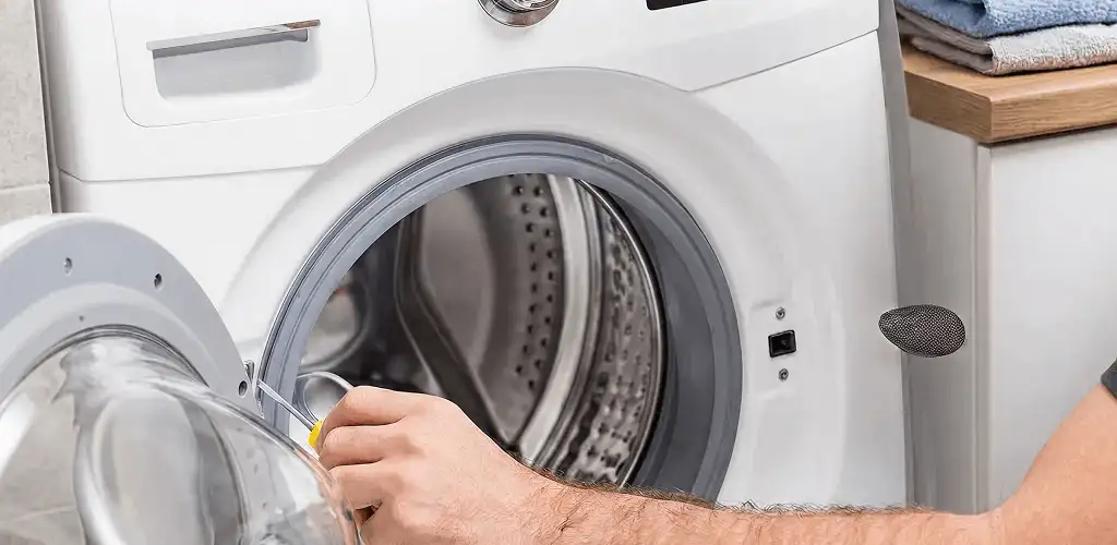 Handyman repairing a front-load washing machine and inspecting the drum in Rockford, IL