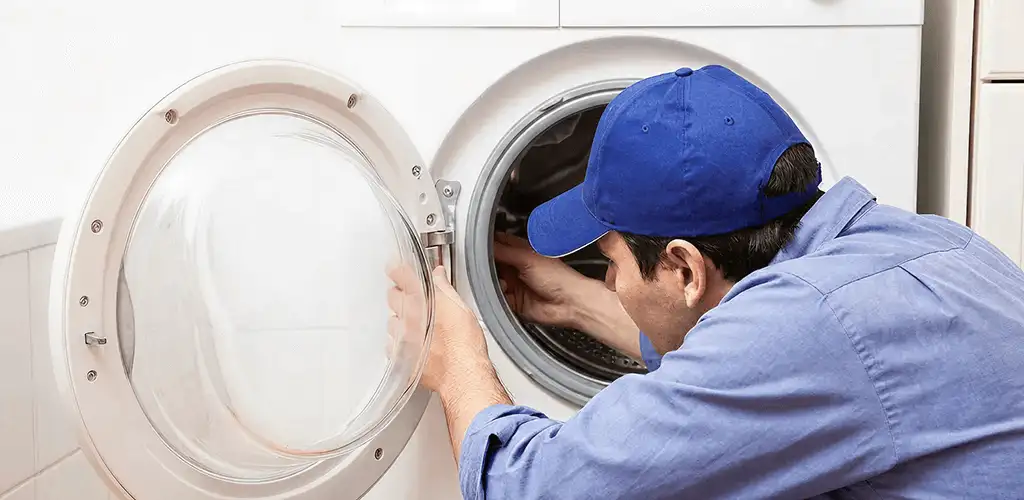 Washing machine repair handyman inspecting a front-load washer drum in Rockford, IL