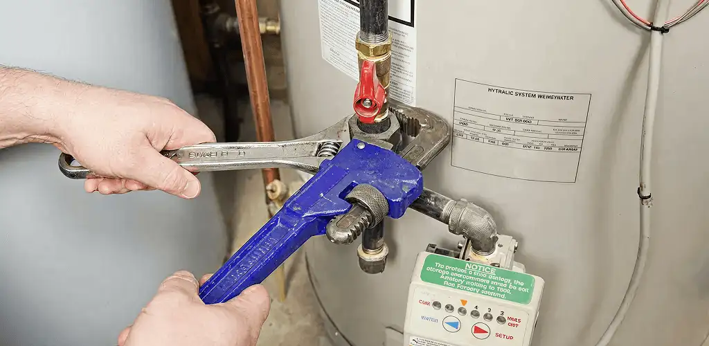 Water heater repair technician tightening the shutoff valve and supply line in Rockford, IL